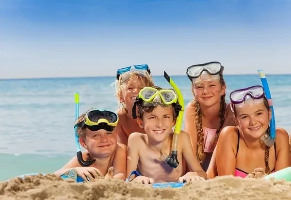 Grupa dzieci z maskami i okularami do pływania na plaży