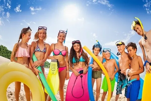 Wakacyjna grupa z kolorowymi kołami do pływania i piłką na plaży
