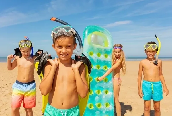 Dzieci z materacem i maskami do pływania podczas plażowania