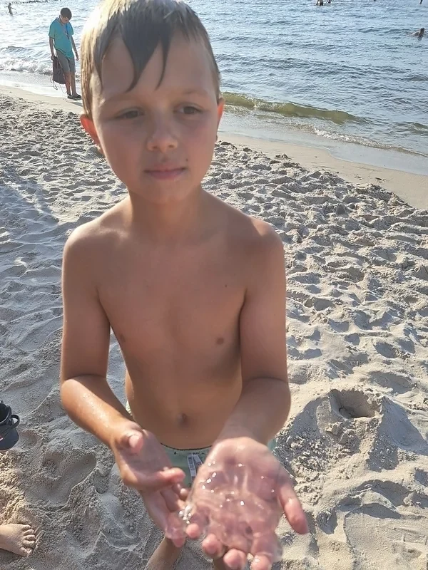 Uczestnik kolonii prezentuje przedmiot znaleziony podczas zabawy na plaży