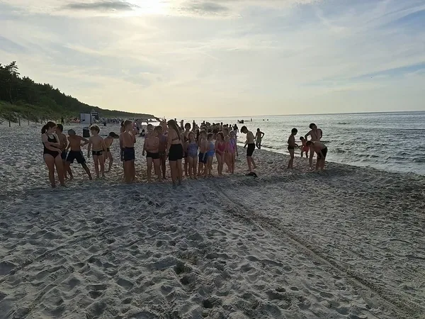Grupa kolonistów podczas wspólnej zabawy na plaży o zachodzie słońca