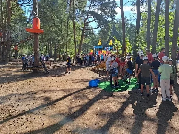 Grupa uczestników kolonii oczekuje przy trasach parku linowego