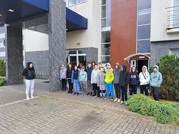 Dzieci z wychowawcą stoją w szeregu przed ośrodkiem wypoczynkowym