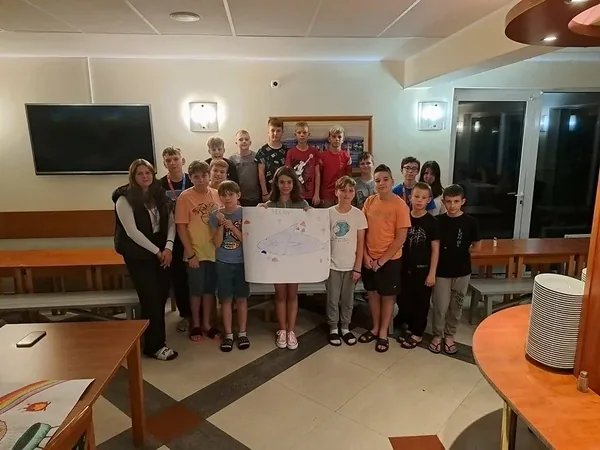 Dzieci pozują z kolorowym plakatem podczas prezentacji grup