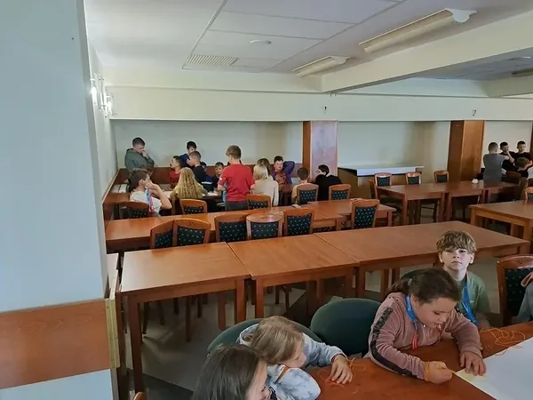 Dzieci siedzą razem przy stołach w jadalni ośrodka