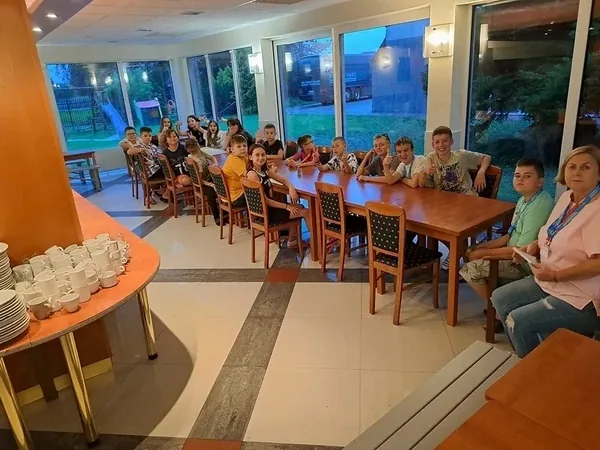Dzieci wspólnie odpoczywają przy długich stołach w ośrodku