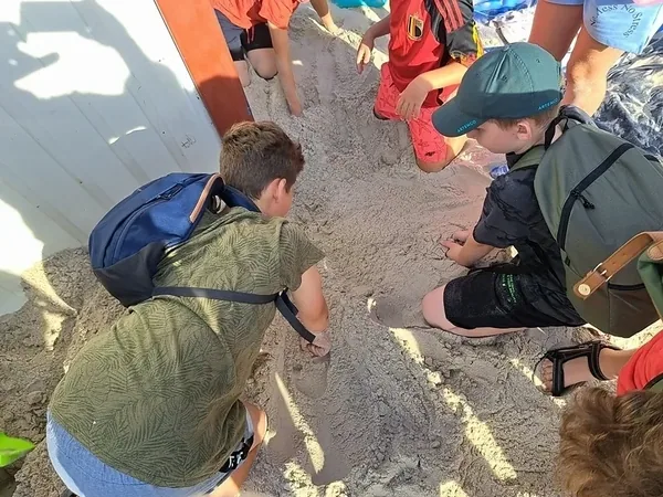 Uczestnicy kolonijnej gry terenowej wspólnie sprawdzają znaleziony przedmiot