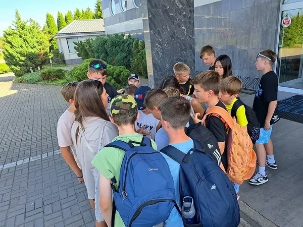 Dzieci z plecakami zbierają się przed wyruszeniem na grę terenową
