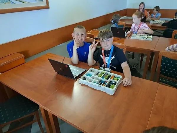 Mali konstruktorzy przy zestawie klocków i laptopie na warsztatach