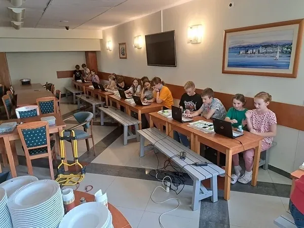 Dzieci z opiekunem podczas praktycznych zajęć z klockami i laptopami
