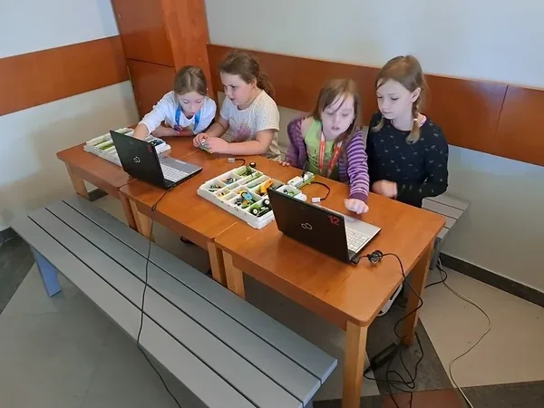 Dzieci pracują z laptopami i uporządkowanymi zestawami klocków