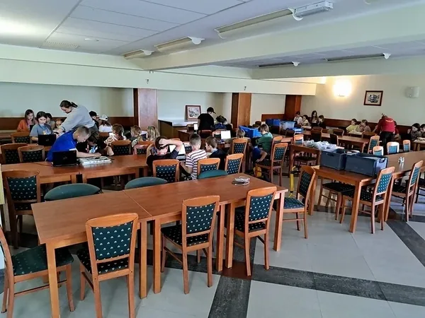 Sala ośrodka przygotowana do warsztatów z robotyki przy drewnianych stołach