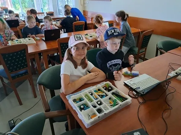 Dzieci przygotowują elementy konstrukcyjne przy laptopie podczas warsztatów