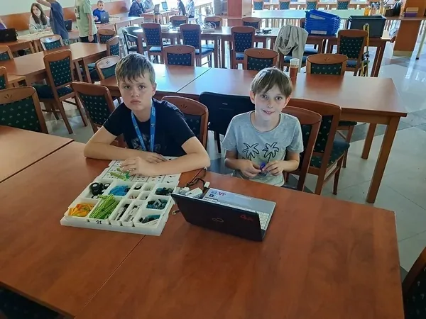 Uczestnicy zajęć edukacyjnych pracują przy laptopie i zestawie do robotyki