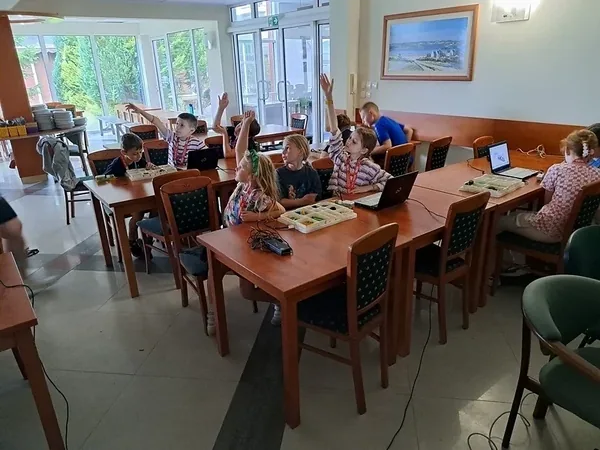 Widok sali z grupami dzieci budujących i programujących roboty